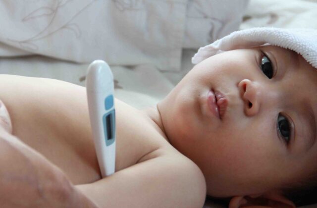 Child with fever being checked with a thermometer — dengue care at home