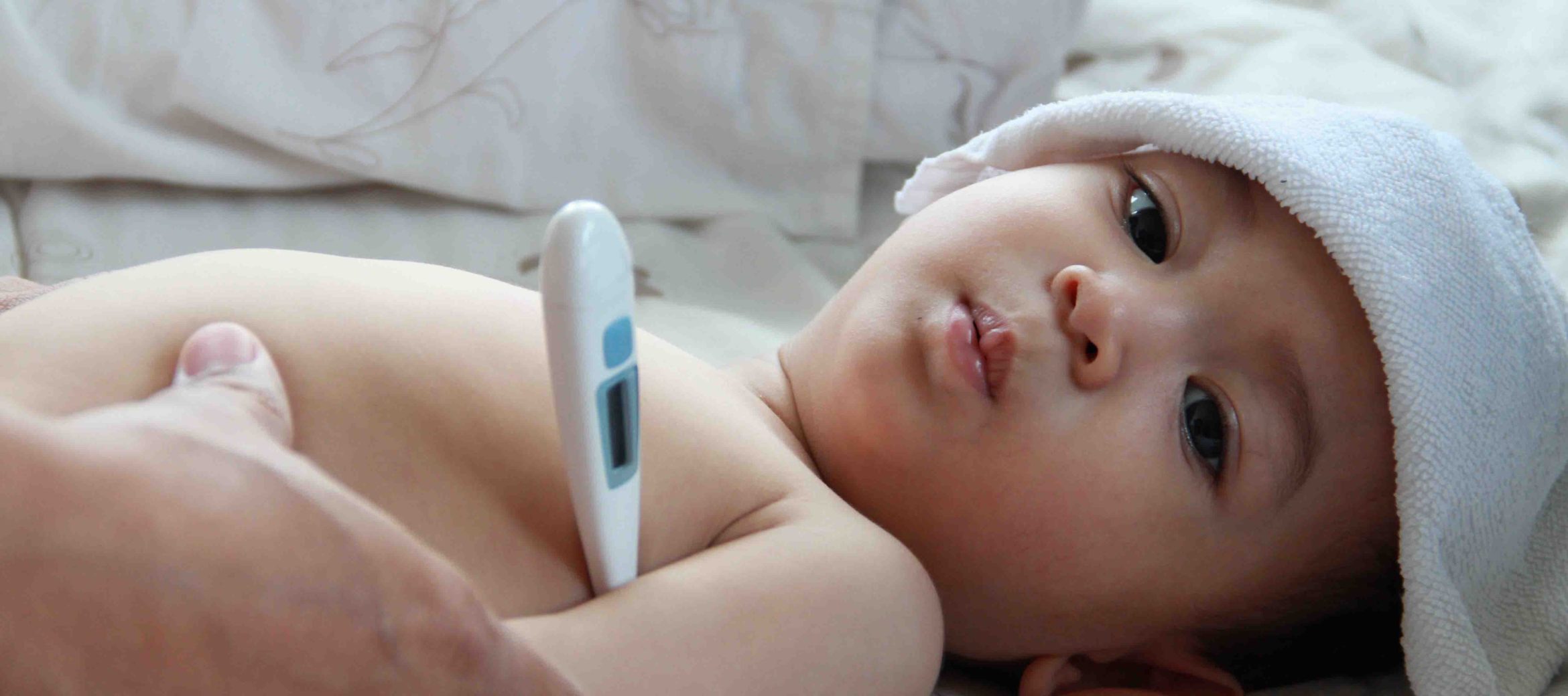Child with fever being checked with a thermometer — dengue care at home
