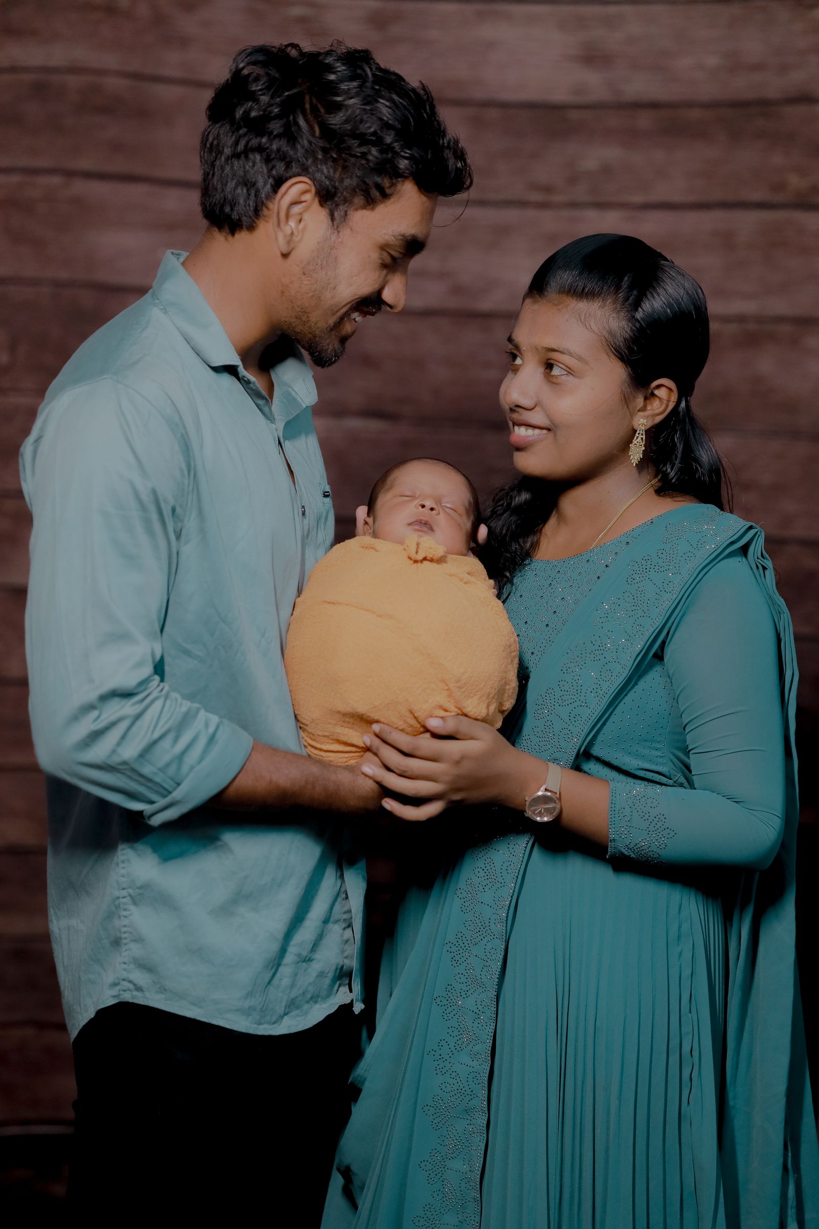 Happy Indian couple with newborn baby in a warm studio portrait — Photo: Dream_maKkerzz / Pexels (free to use)