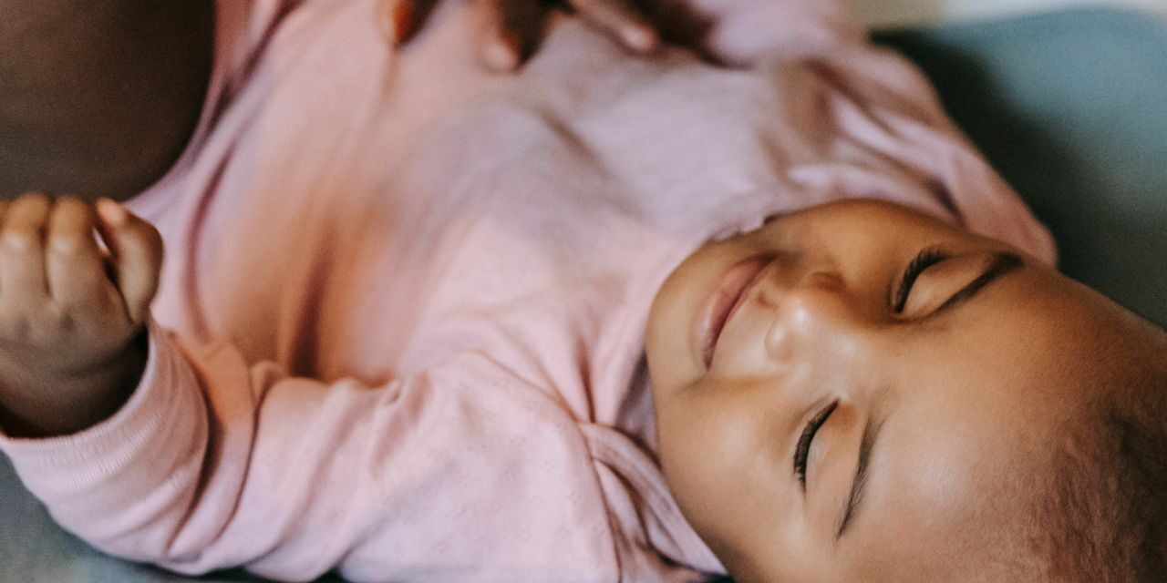 Well-dressed Indian mother gently watching her peaceful infant at home on a clean modern changing mat