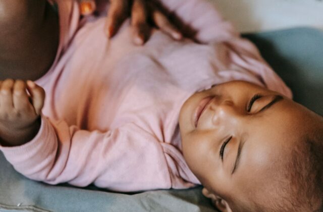 Well-dressed Indian mother gently watching her peaceful infant at home on a clean modern changing mat