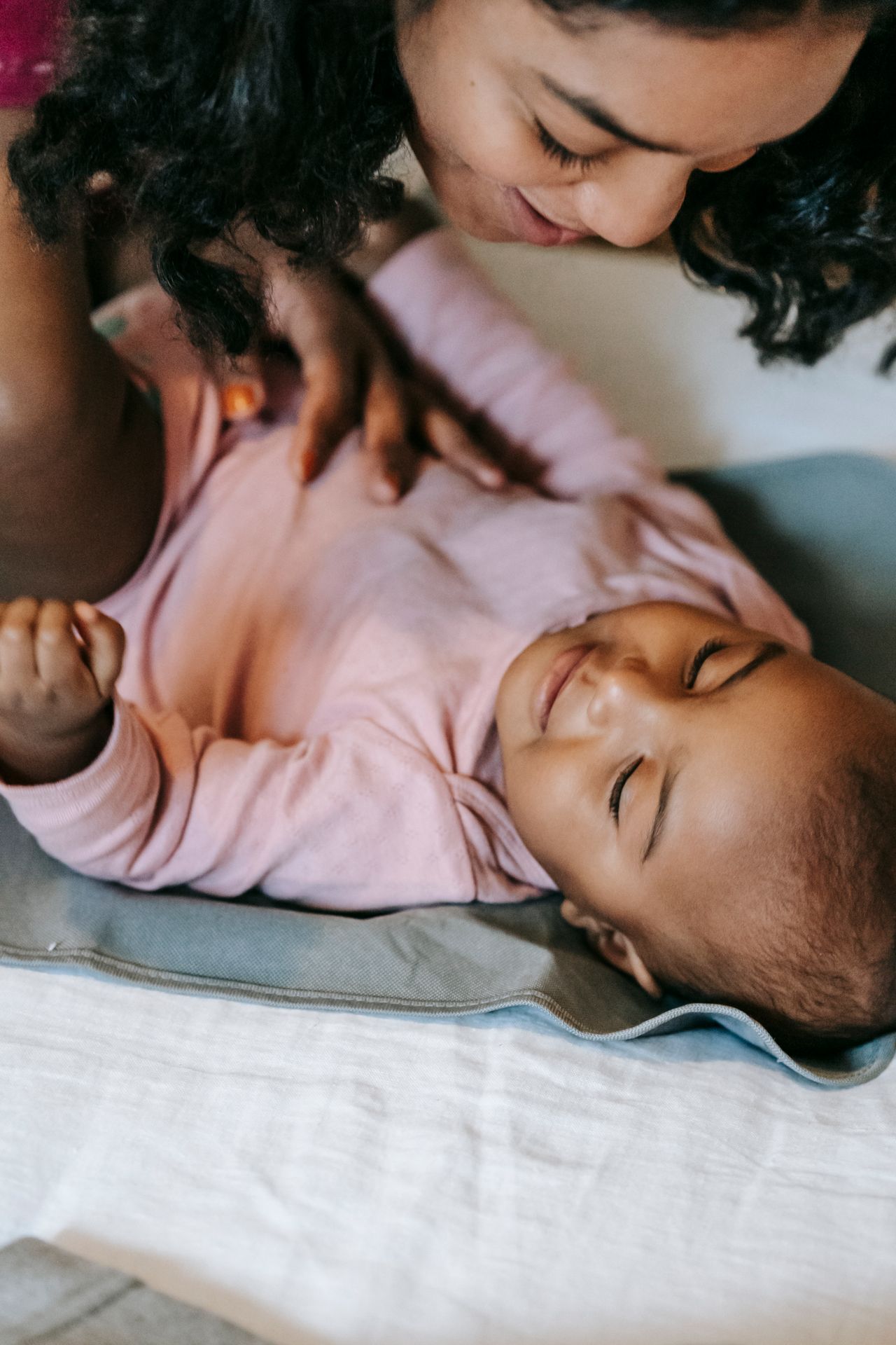 Well-dressed Indian mother gently watching her peaceful infant at home on a clean modern changing mat
