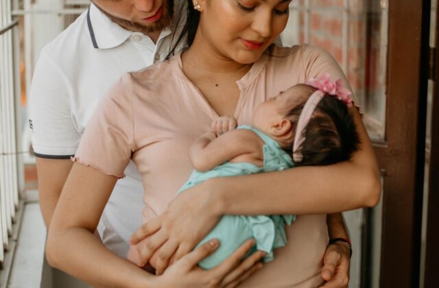 Well-to-do Indian parents cradling their newborn baby at home