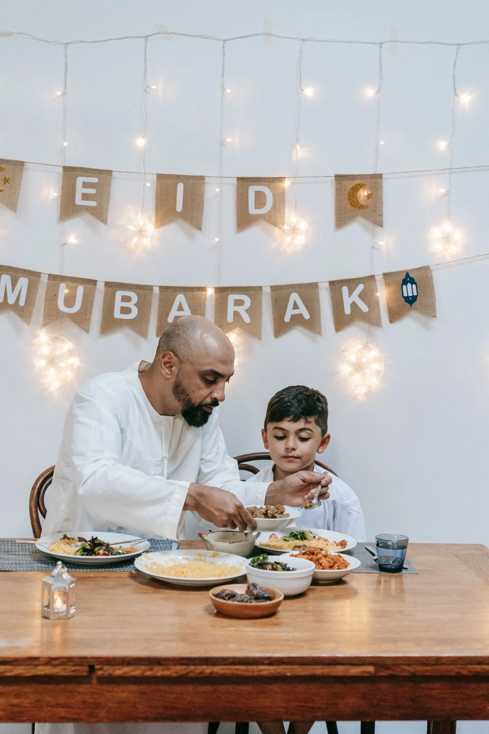 Well-dressed South Asian father and young son sharing a healthy home meal with rice and salad at the dining table