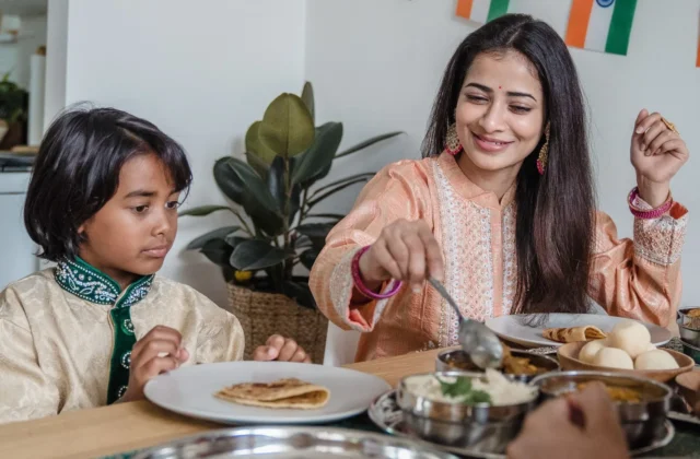 Indian mother and young son sharing a healthy home meal of dal and paratha at the dining table