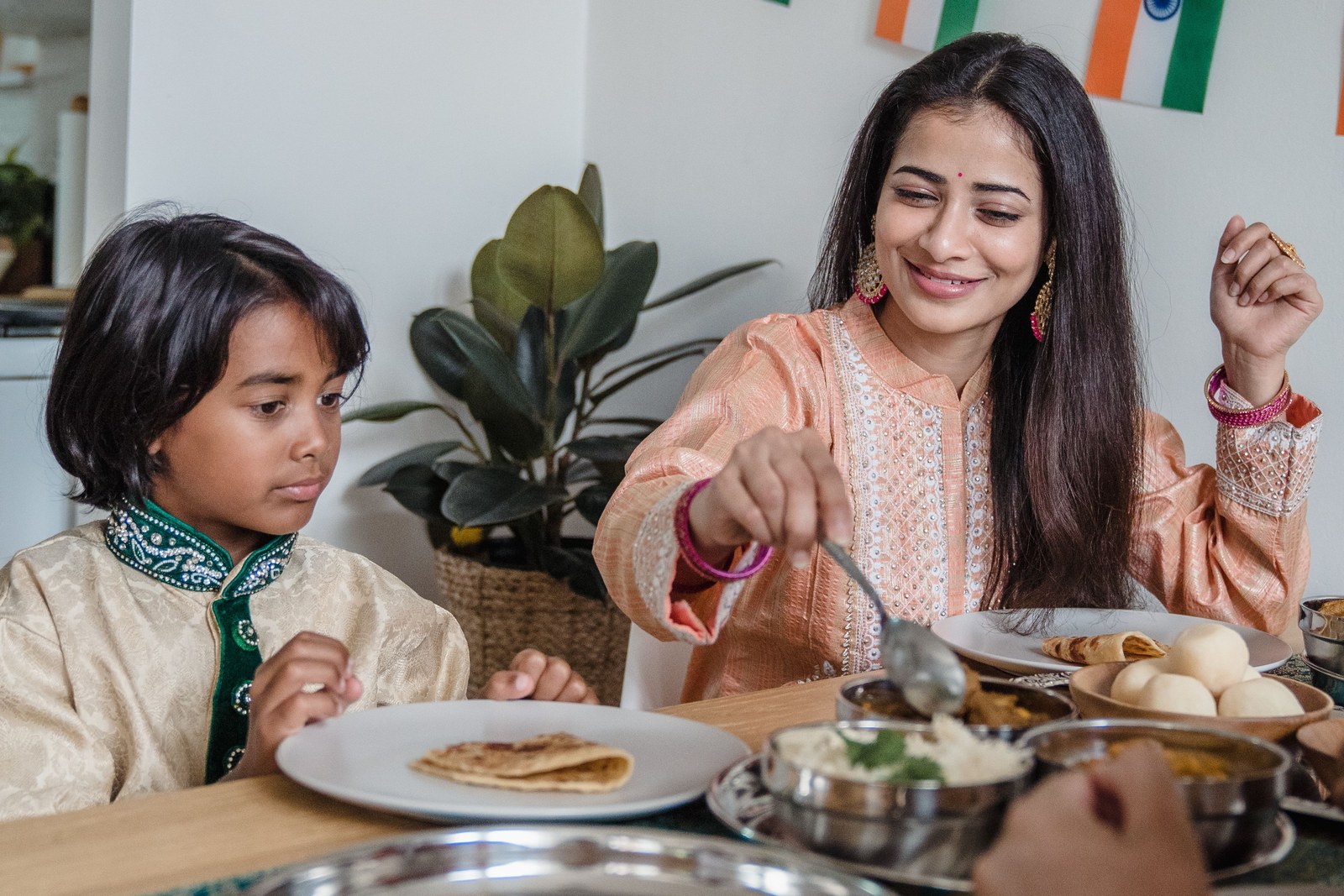 Indian mother and young son sharing a healthy home meal of dal and paratha at the dining table